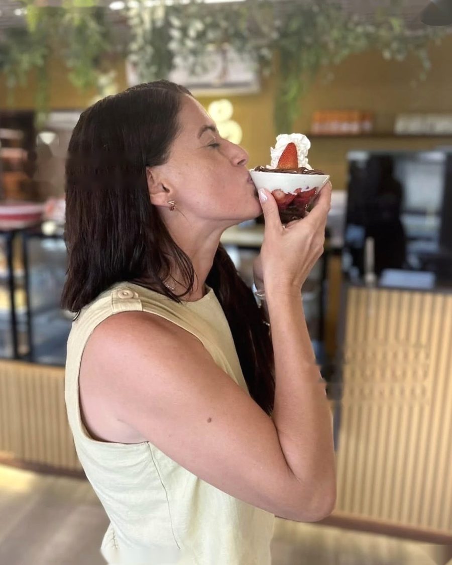 Marina Araújo, nutricionista, tomando uma sobremesa de morango com chantilly em uma cafeteria.