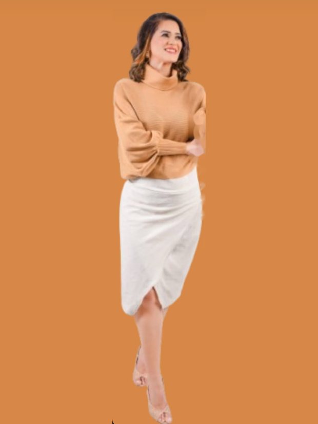 Marina Araújo em pé, de suéter e saia, sorrindo.